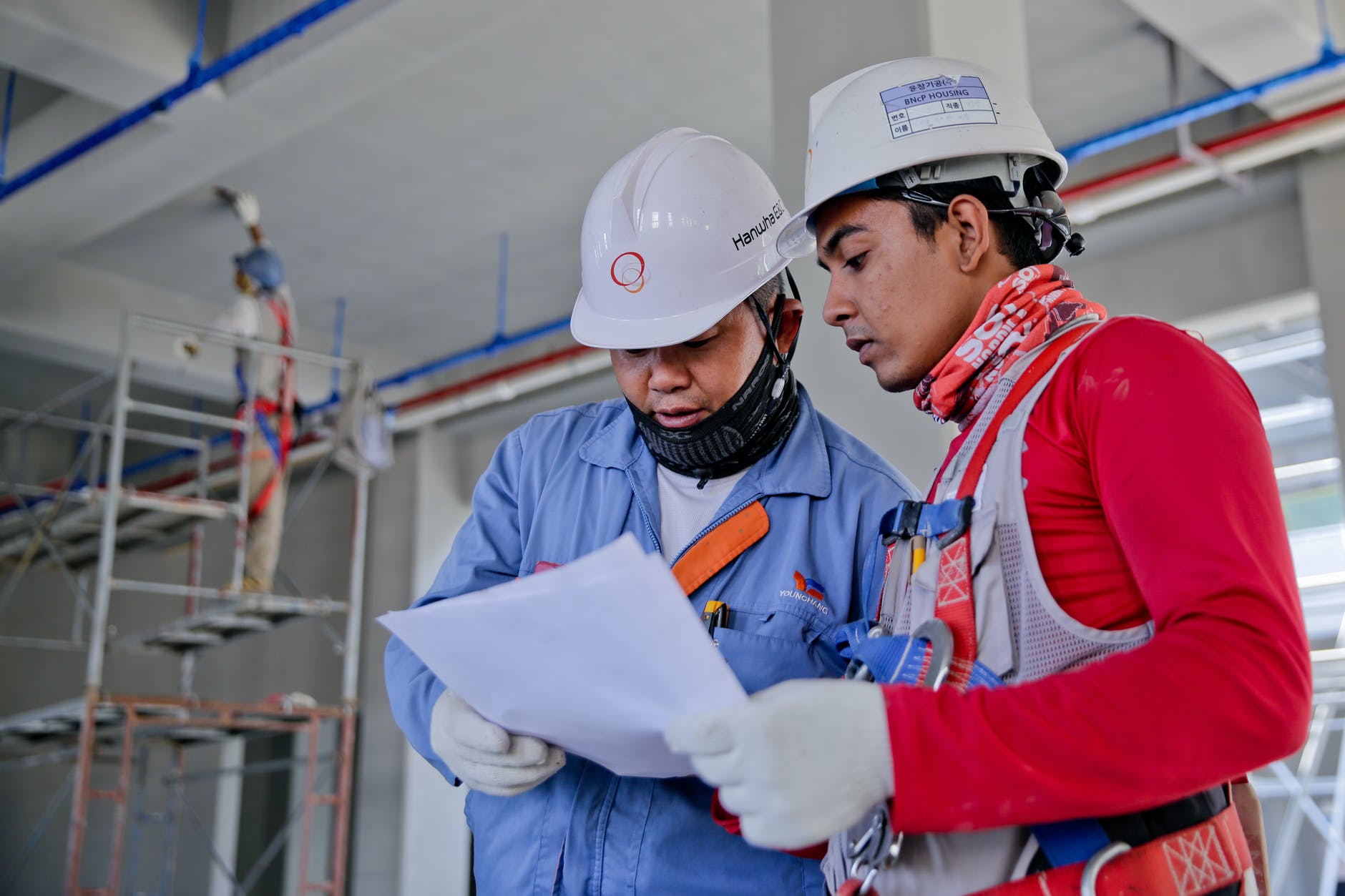 2 Trabajadores con cascos viendo un documento.